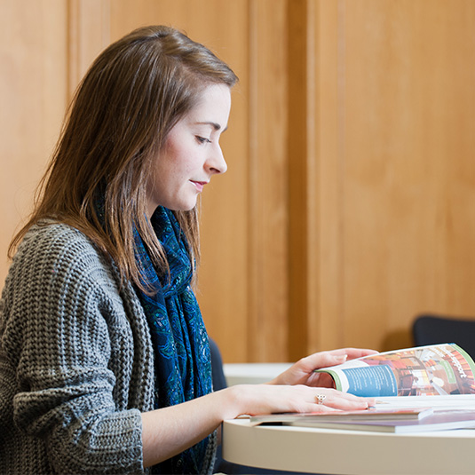 female student reading textbook in the McClay library
