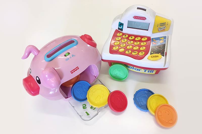 toy piggy bank with colourful plastic coins scattered beside it