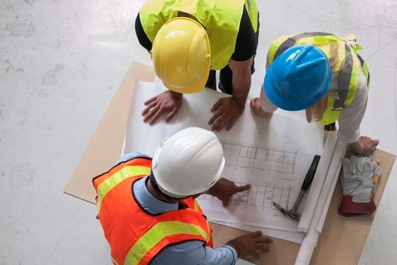 3 people in hard hats look at a plan