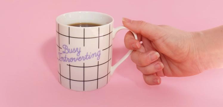 Person holding mug labelled Busy Introverting