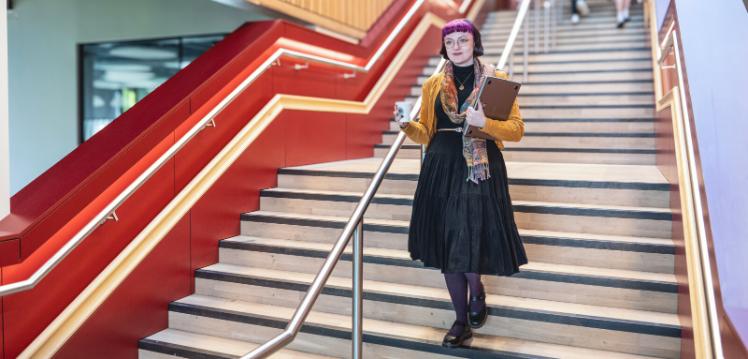 Student Emma walks down stairs in One Elmwood