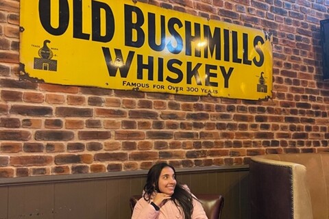 Student sitting in front of Old Bushmills whiskey sign