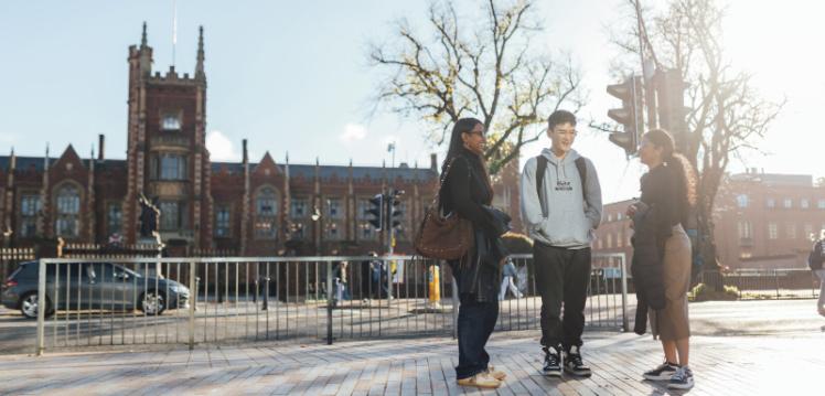 Three students stand together across the road from the Lanyon