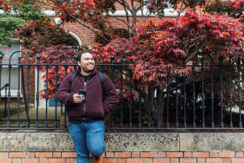 Student Miguel stands against fence in University Street