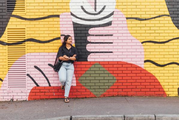 Female student standing against Guinness graffiti art in Belfast