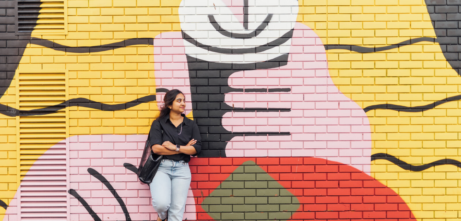 Female student leaning against graffiti art in Belfast