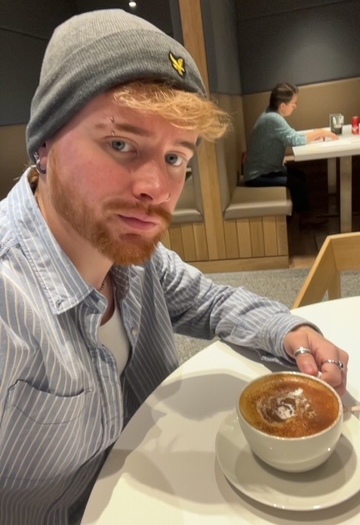Student Scott holds cup of coffee