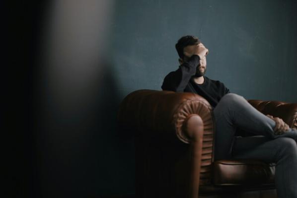 Man sitting on sofa looking stressed out
