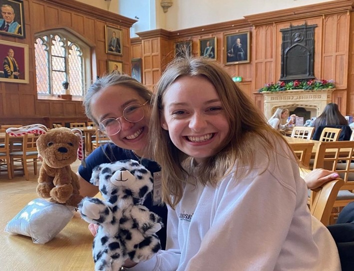 Two students smiling and holding a cuddly toy