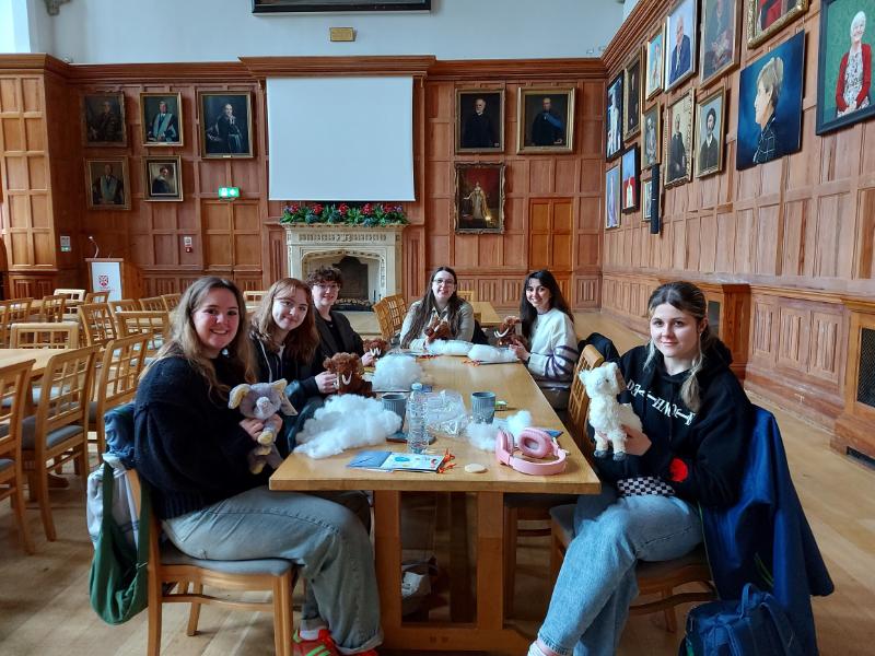 smiling students sitting at a table with assorted cuddly toys
