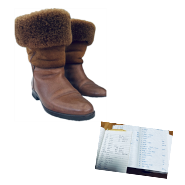 A pair of brown furry boots placed next to open books and copybooks.
